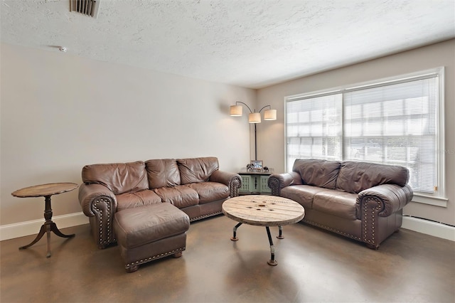 living area with finished concrete flooring, baseboards, visible vents, and a textured ceiling