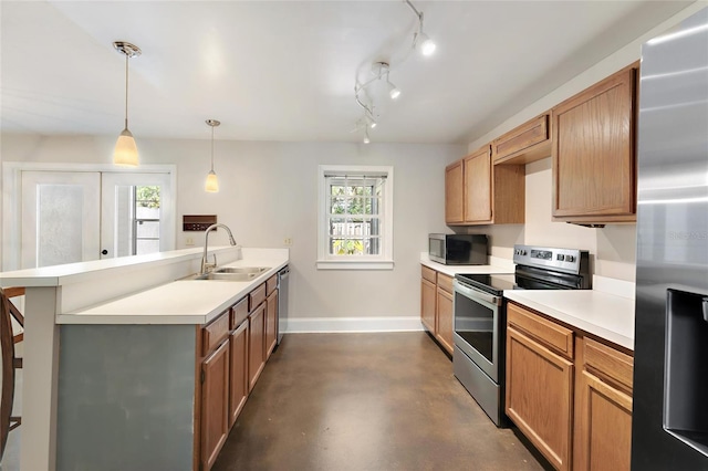 kitchen with baseboards, a peninsula, a sink, stainless steel appliances, and light countertops