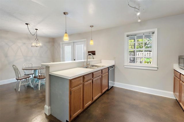 kitchen with brown cabinetry, finished concrete flooring, baseboards, a peninsula, and a sink