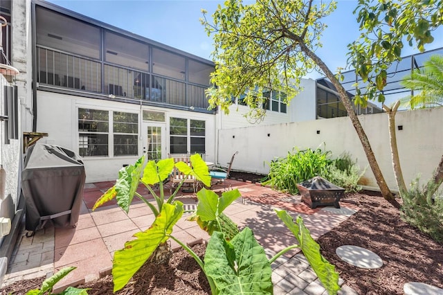 rear view of property featuring a patio area, a fire pit, fence, and stucco siding