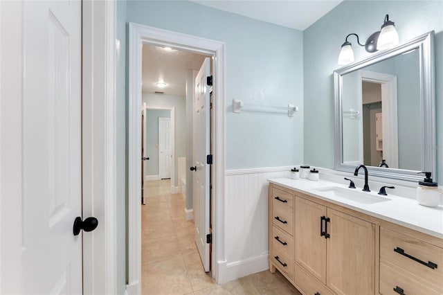 bathroom with a wainscoted wall, vanity, and tile patterned flooring