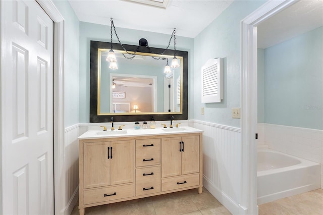 bathroom featuring tile patterned floors, double vanity, a wainscoted wall, and a sink