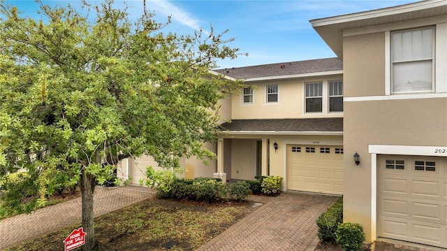 view of front of house with a shingled roof, an attached garage, driveway, and stucco siding