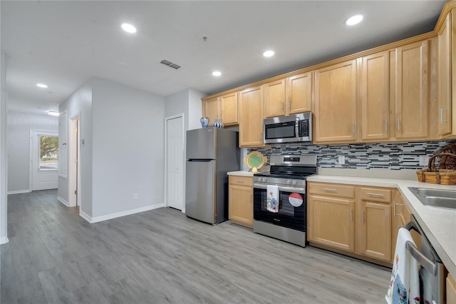 kitchen with light brown cabinets, backsplash, appliances with stainless steel finishes, and light wood-type flooring