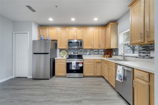 kitchen featuring light brown cabinetry, appliances with stainless steel finishes, and a sink