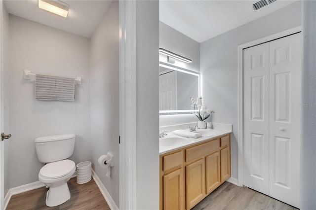 full bath featuring a closet, wood finished floors, toilet, and a sink