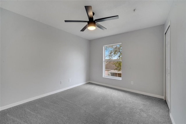 carpeted spare room featuring baseboards and a ceiling fan