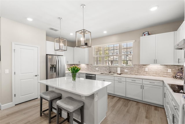 kitchen with a kitchen island, a breakfast bar area, decorative backsplash, appliances with stainless steel finishes, and a sink