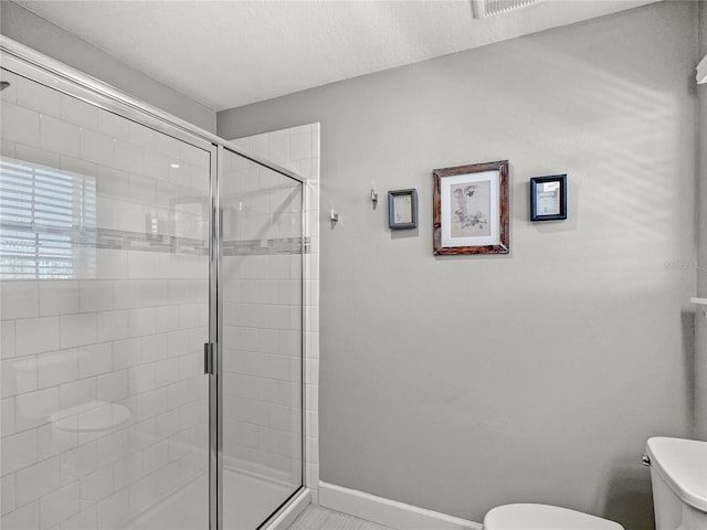 full bathroom featuring a shower stall, toilet, and baseboards