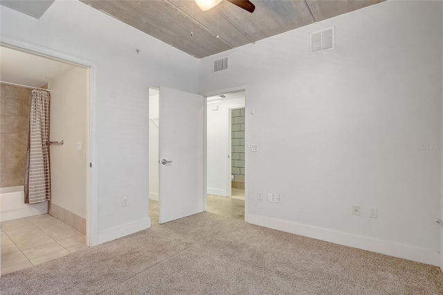 unfurnished bedroom featuring tile patterned floors, visible vents, carpet floors, and a walk in closet