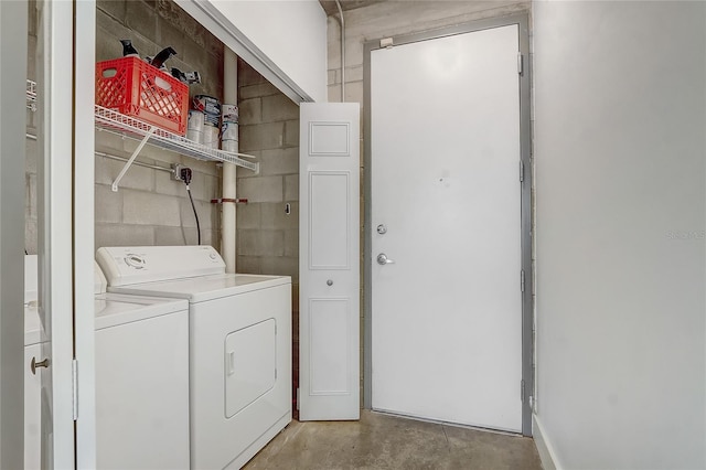 washroom with laundry area, concrete block wall, and independent washer and dryer