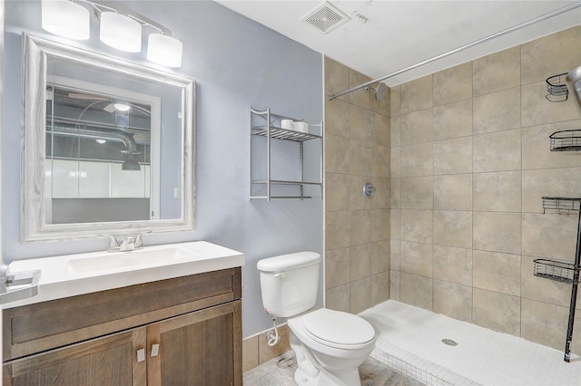 bathroom with toilet, visible vents, and tiled shower