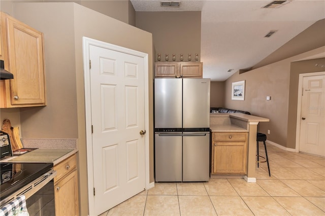 kitchen featuring visible vents, light countertops, vaulted ceiling, freestanding refrigerator, and light tile patterned flooring