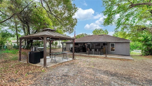 rear view of property with a gazebo, a patio, roof with shingles, and fence