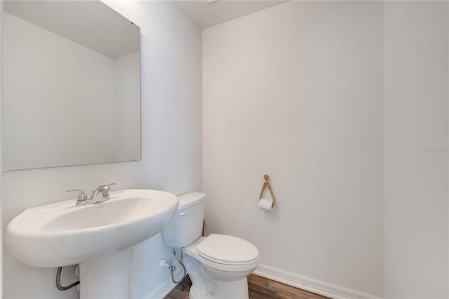 bathroom with a sink, baseboards, toilet, and wood finished floors