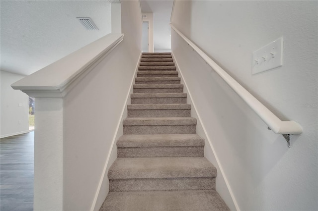 stairs with visible vents, baseboards, and wood finished floors