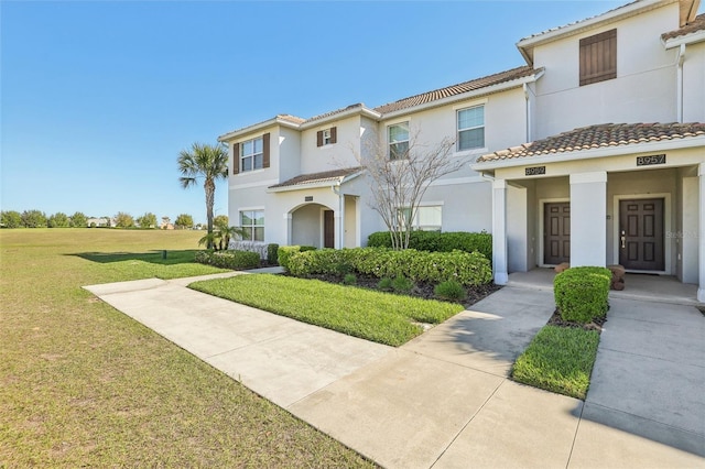 view of front of property with a front lawn, a tile roof, and stucco siding