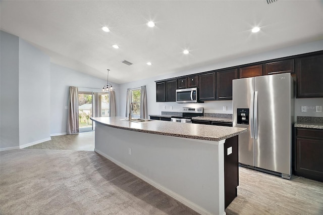 kitchen featuring lofted ceiling, recessed lighting, a kitchen island with sink, a sink, and appliances with stainless steel finishes