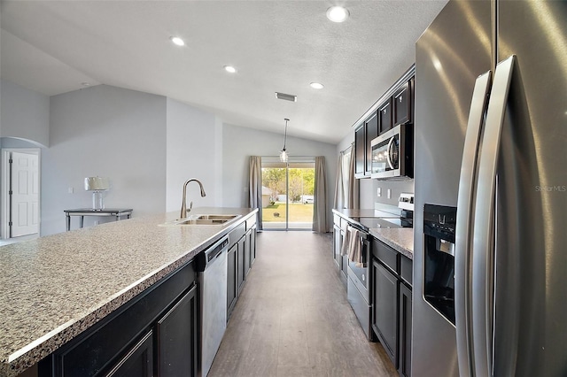 kitchen with visible vents, light wood-style flooring, a sink, stainless steel appliances, and lofted ceiling