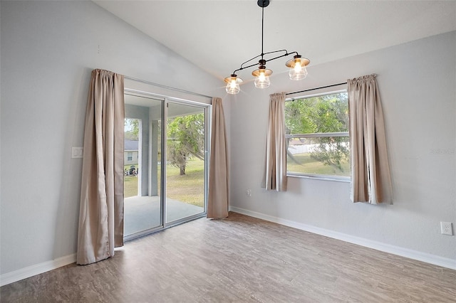 spare room with a chandelier, a healthy amount of sunlight, baseboards, and lofted ceiling