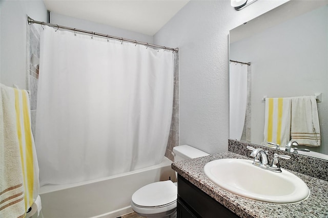 bathroom with vanity, shower / tub combo, toilet, and a textured wall