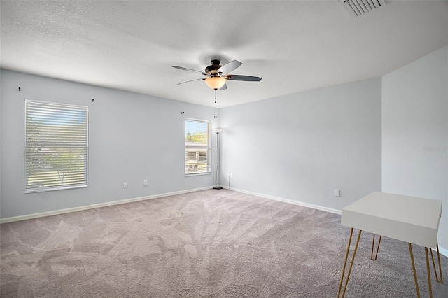 spare room with baseboards, visible vents, ceiling fan, a textured ceiling, and carpet flooring
