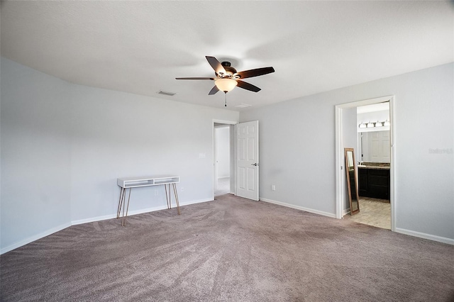 unfurnished bedroom with a ceiling fan, visible vents, carpet, baseboards, and ensuite bath