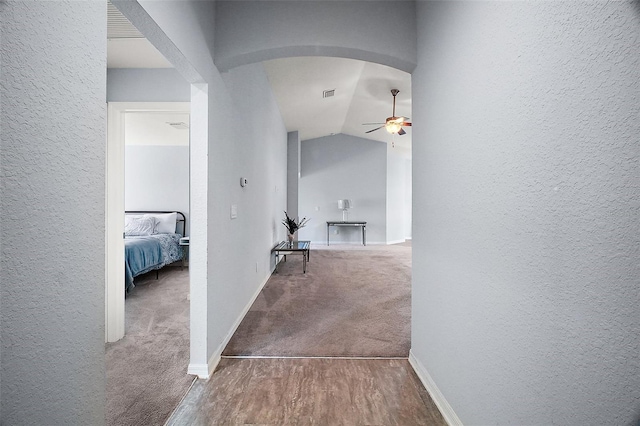 corridor featuring arched walkways, visible vents, baseboards, and a textured wall