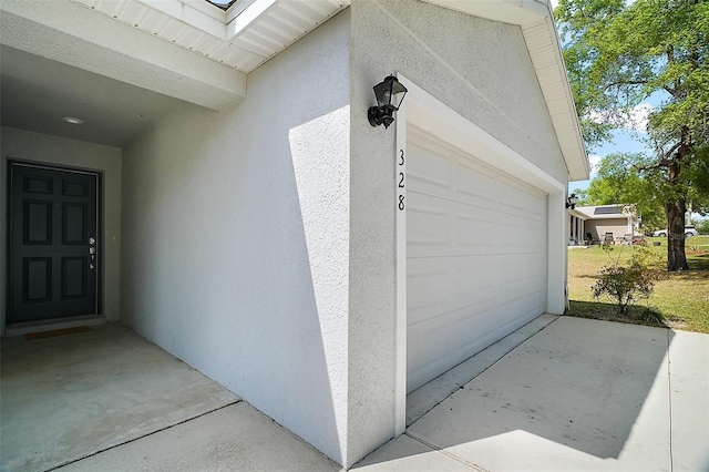 property entrance featuring stucco siding, concrete driveway, and an attached garage
