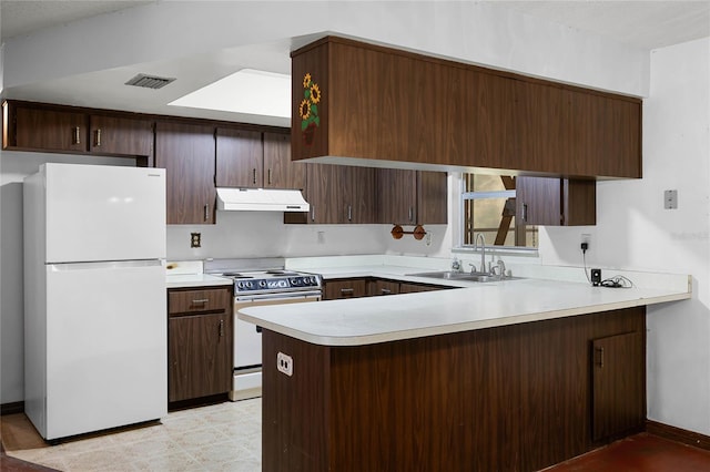 kitchen featuring under cabinet range hood, light countertops, electric range oven, freestanding refrigerator, and a sink