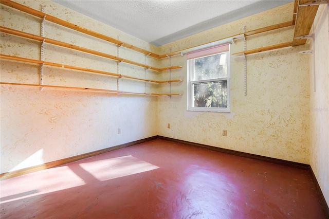 unfurnished room with a textured ceiling, finished concrete flooring, and baseboards