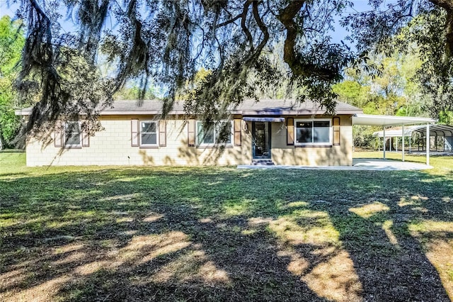 ranch-style home featuring an attached carport, driveway, concrete block siding, and a front yard