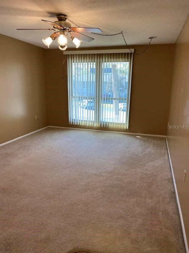 unfurnished room featuring baseboards, carpet floors, a textured ceiling, and a ceiling fan