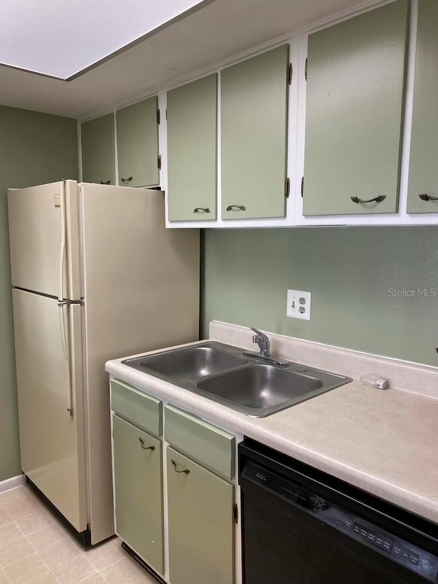 kitchen with a sink, black dishwasher, freestanding refrigerator, light countertops, and green cabinetry