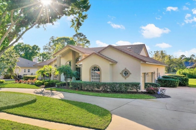 mediterranean / spanish-style home featuring curved driveway, a tile roof, a front lawn, and stucco siding