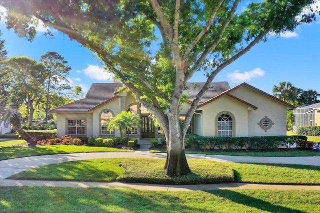 view of front facade with stucco siding, a front lawn, and a tile roof