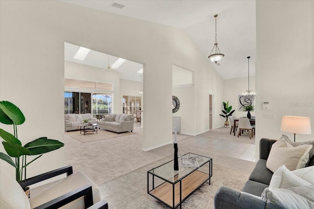 carpeted living area featuring visible vents, ceiling fan with notable chandelier, high vaulted ceiling, and baseboards