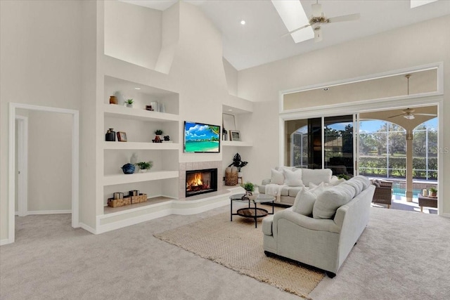 carpeted living area featuring built in features, a ceiling fan, a warm lit fireplace, and high vaulted ceiling