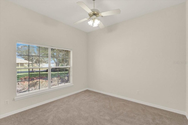 carpeted empty room with a ceiling fan and baseboards