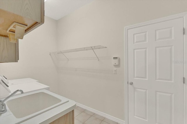 laundry area with washer and clothes dryer, a sink, light tile patterned flooring, baseboards, and laundry area