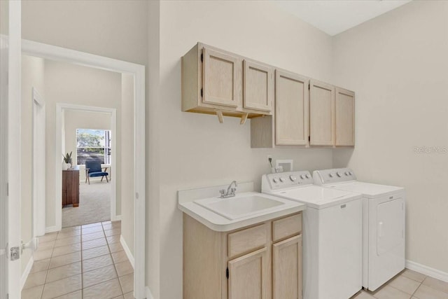 laundry area featuring baseboards, light tile patterned flooring, separate washer and dryer, cabinet space, and a sink