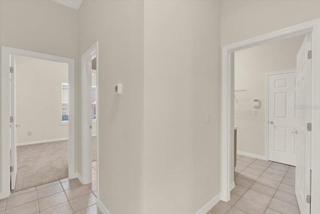 corridor featuring light tile patterned flooring and baseboards