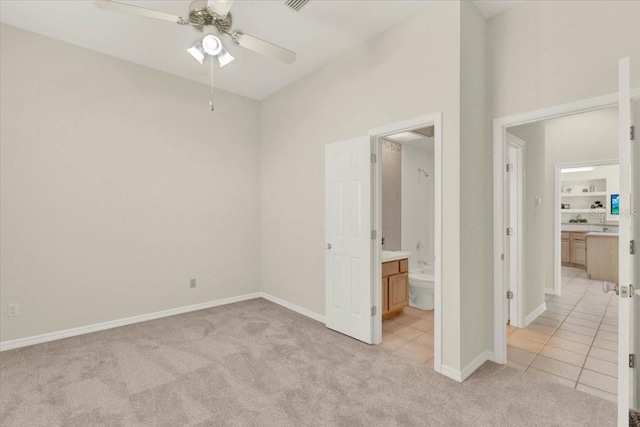 unfurnished bedroom with light tile patterned floors, light colored carpet, baseboards, and connected bathroom