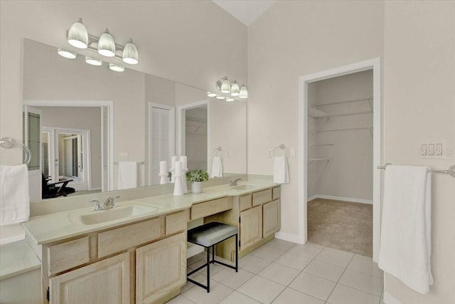 bathroom featuring a sink, a walk in closet, double vanity, and tile patterned flooring