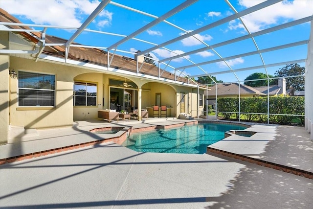 view of swimming pool featuring glass enclosure, a pool with connected hot tub, ceiling fan, and a patio area