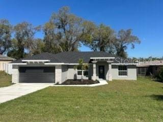 view of front of house featuring a front yard, concrete driveway, and an attached garage