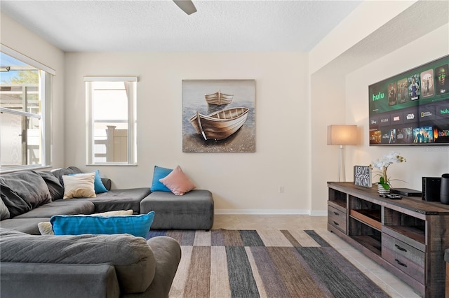 living area featuring light tile patterned floors, baseboards, and a textured ceiling