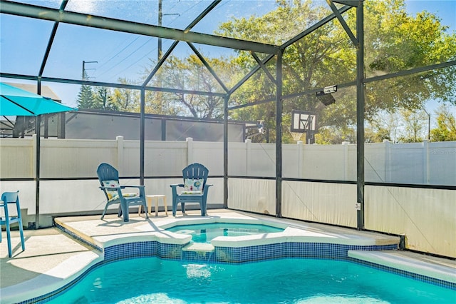 view of pool with a lanai, fence, a pool with connected hot tub, and a patio