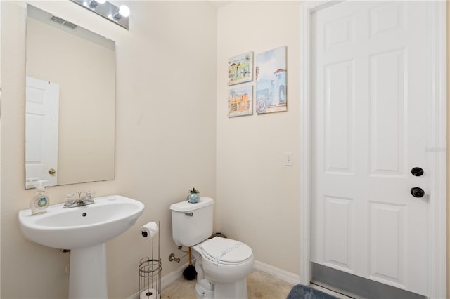 half bathroom featuring toilet, baseboards, visible vents, and a sink