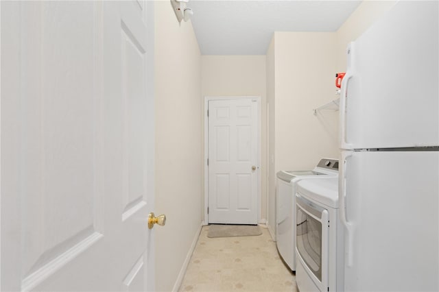 clothes washing area with baseboards, light floors, laundry area, and washer and clothes dryer